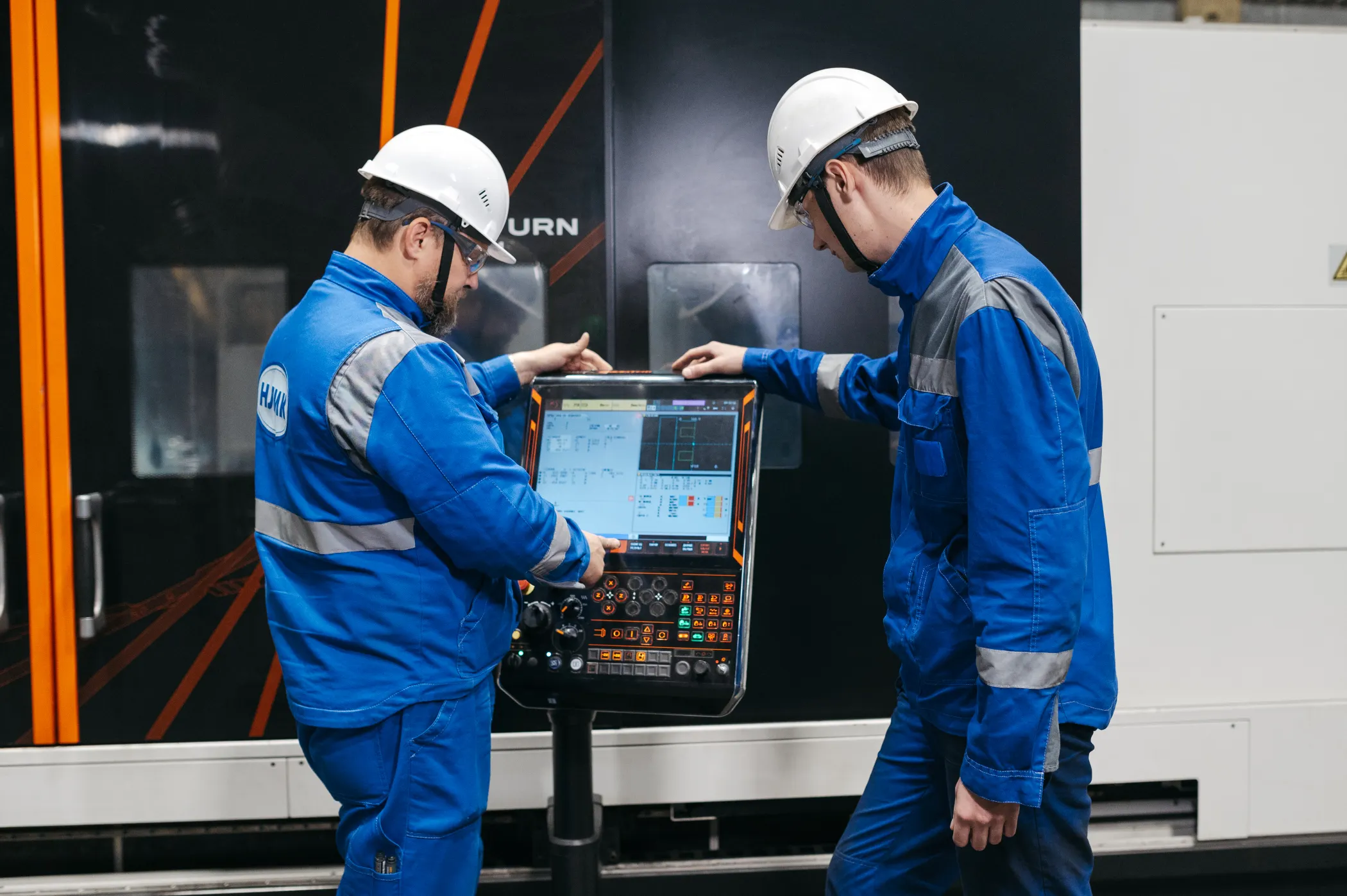 Zwei Fachkräfte arbeiten gemeinsam an einer CNC-Steuerung