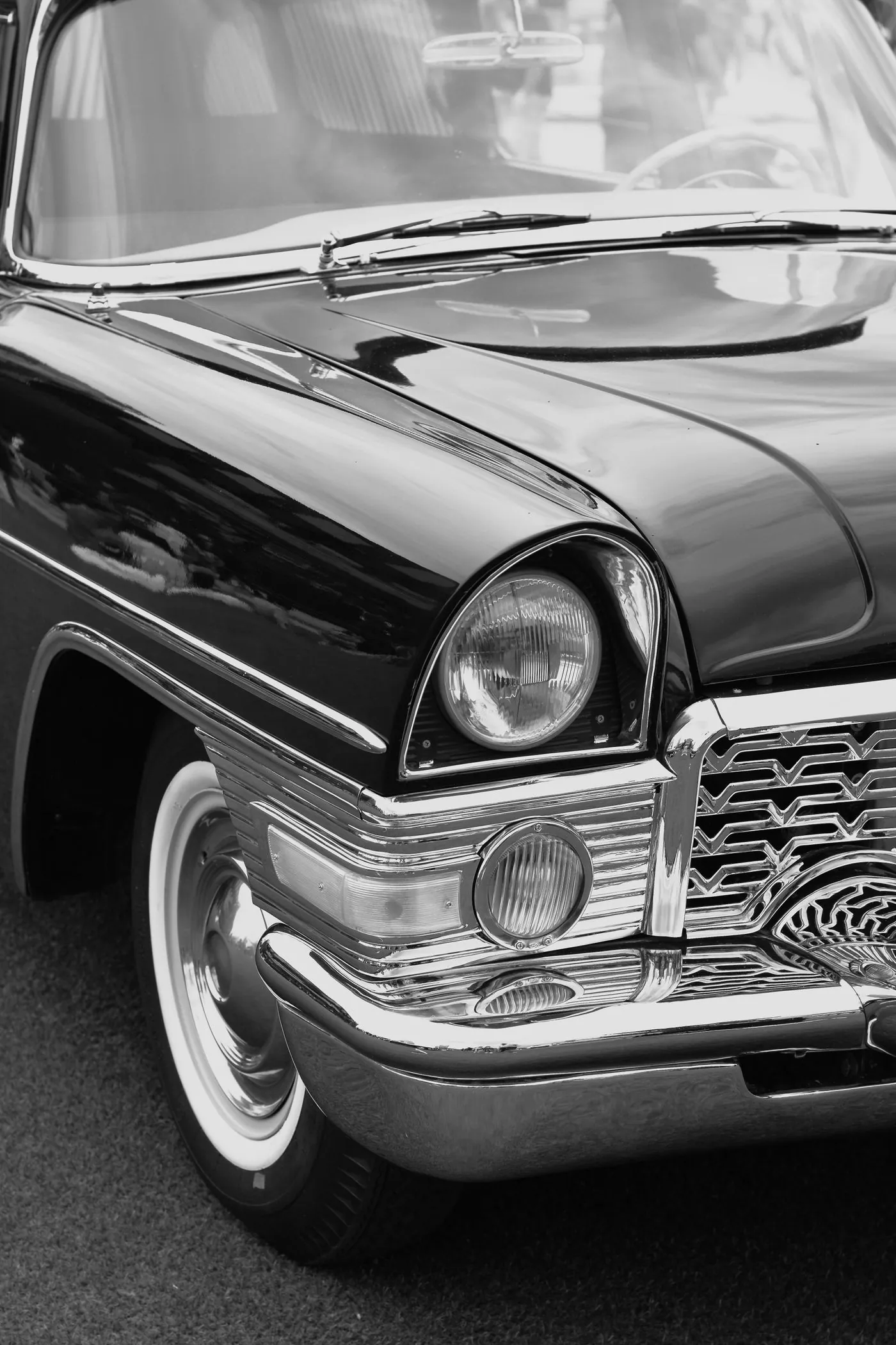 Chromdetails und Scheinwerfer eines klassischen Fahrzeugs in Schwarzweiß