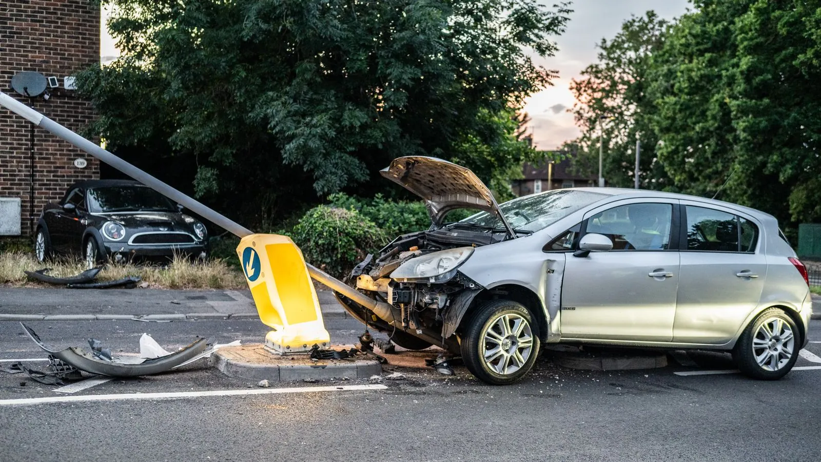 Silberner Kleinwagen nach einem Aufprall gegen einen Laternenmast, Motorhaube aufgestellt