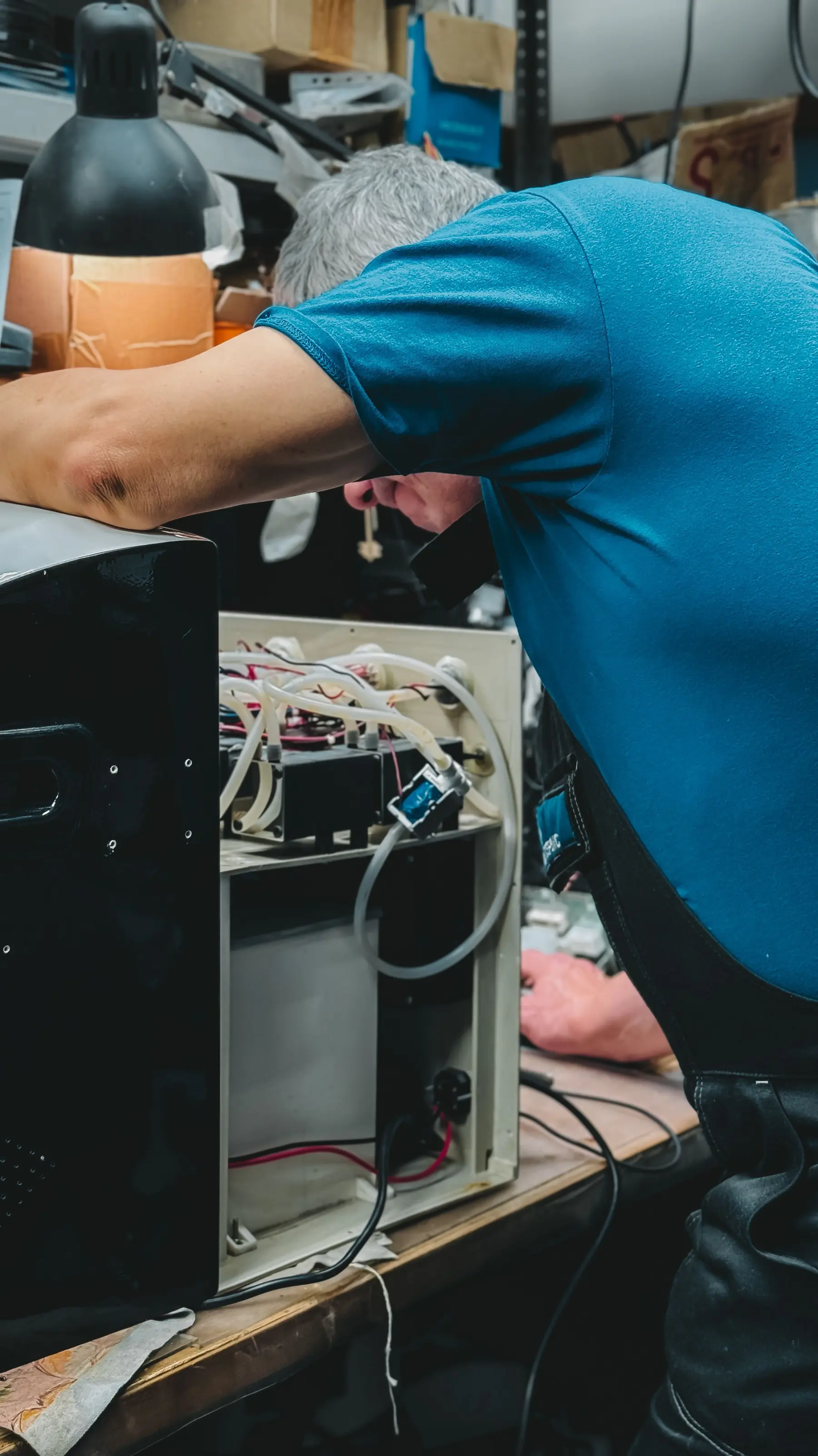 Techniker arbeitet an einem geöffneten Gerät mit Schläuchen und Elektronik