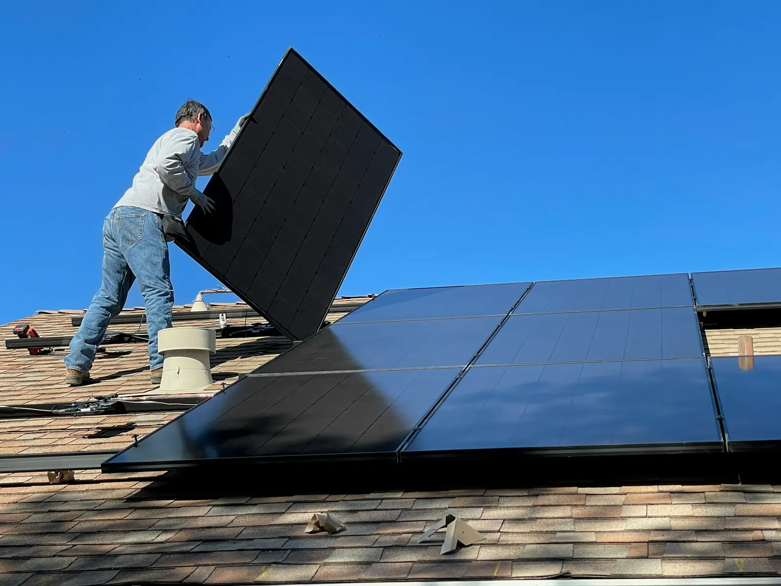 Monteur setzt ein Solarmodul auf ein Schrägdach
