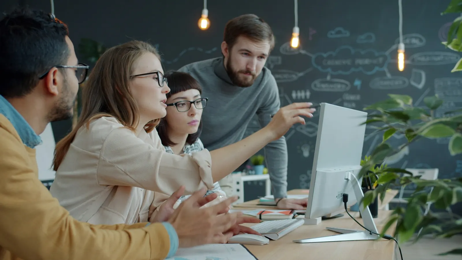 Junges Team arbeitet gemeinsam am Bildschirm in einem hellen Büro