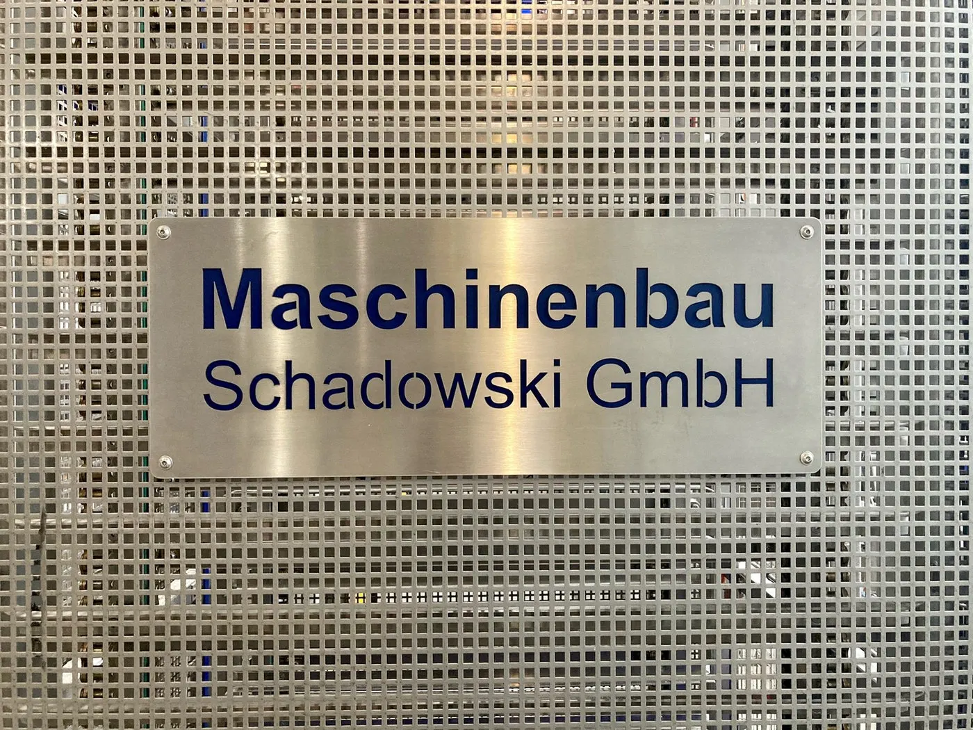 Firmenschild der Maschinenbau Schadowski GmbH an einer Lochblechwand