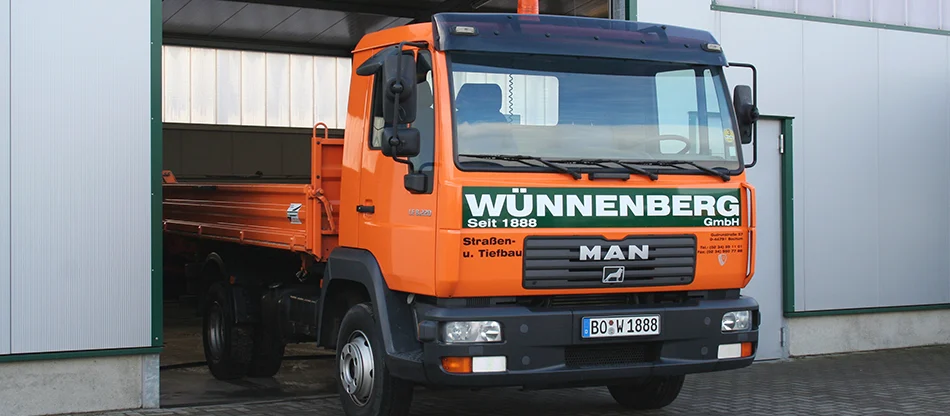 Orangefarbener MAN-Kipper der A. Wünnenberg GmbH vor der Fahrzeughalle