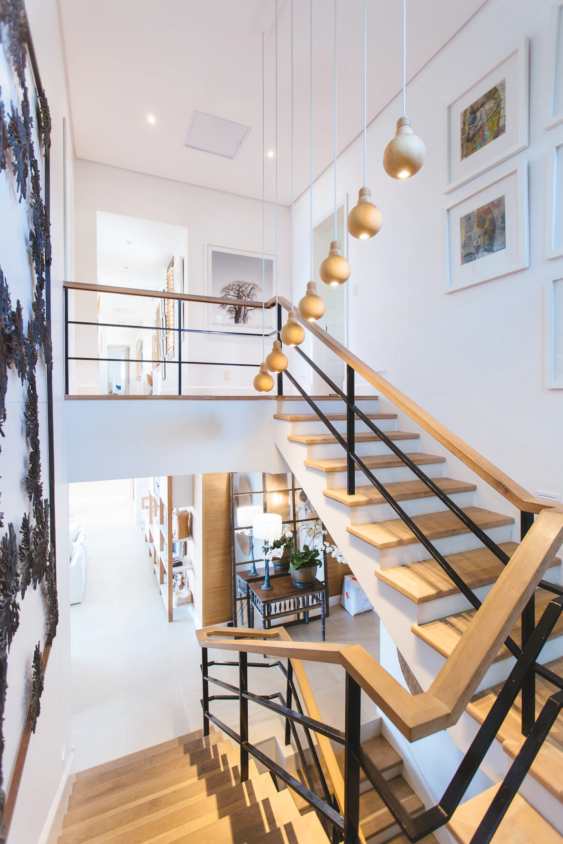 Helles Treppenhaus mit Holztreppe und Bildern an der Wand