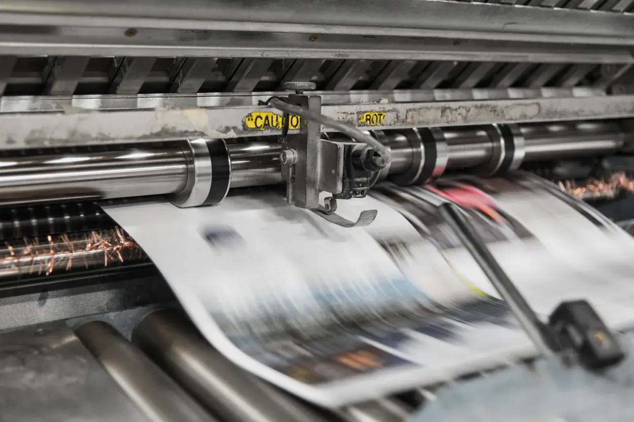 Druckfachkraft prüft die Druckqualität an der Offsetmaschine