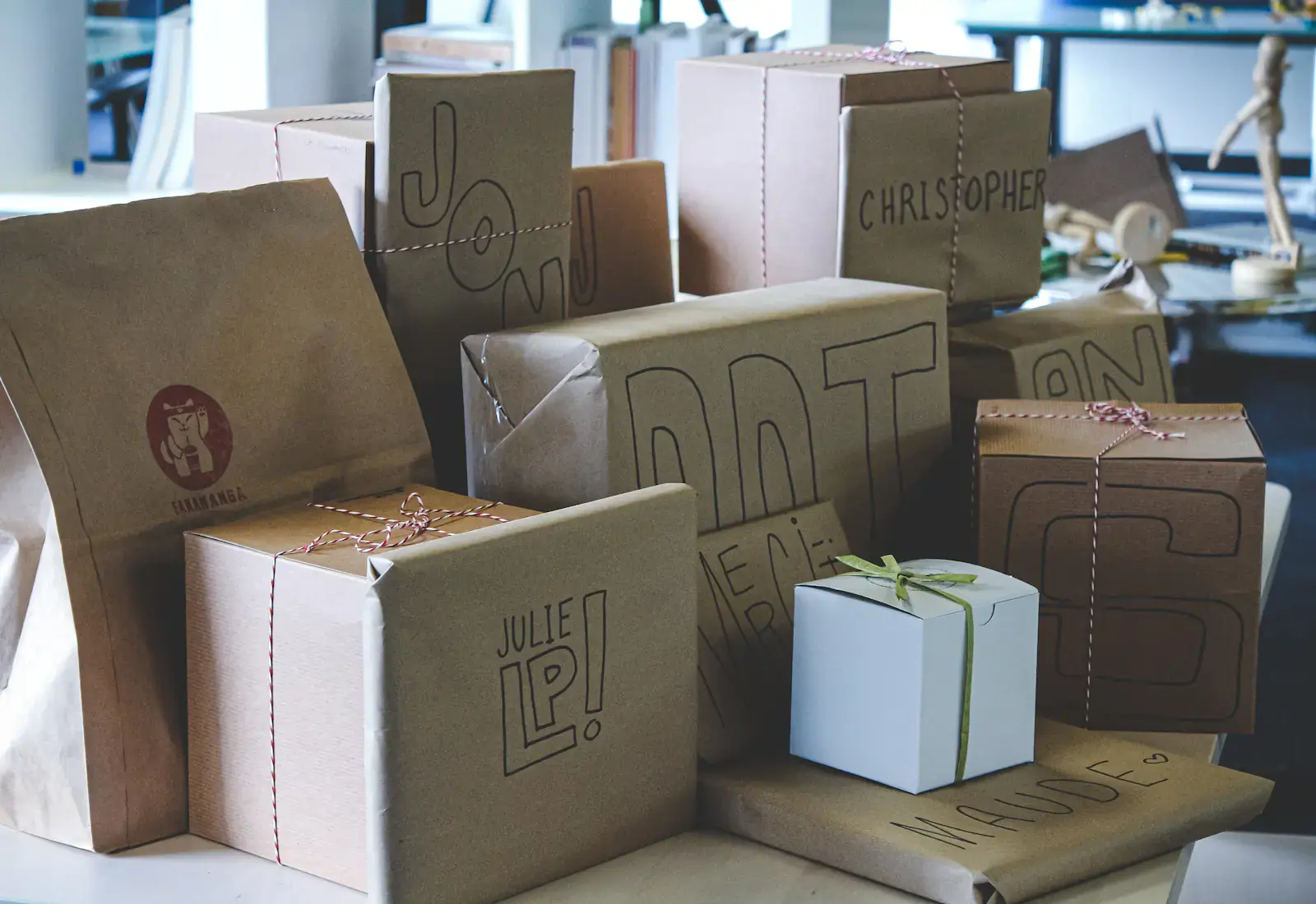 Individuell bedruckte Kraftpapier-Verpackungen und eine weiße Geschenkschachtel mit grünem Band
