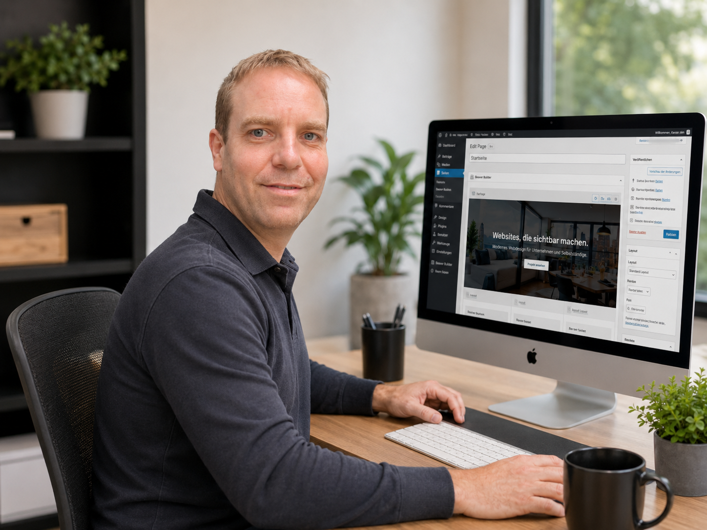 Mann am Schreibtisch vor einem iMac, der eine Website im Bearbeitungsmodus zeigt